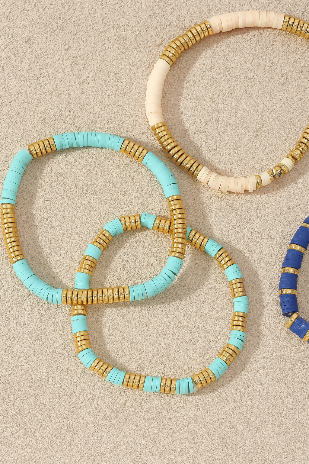 Three beaded bracelets in turquoise, gold, and blue on a beige background