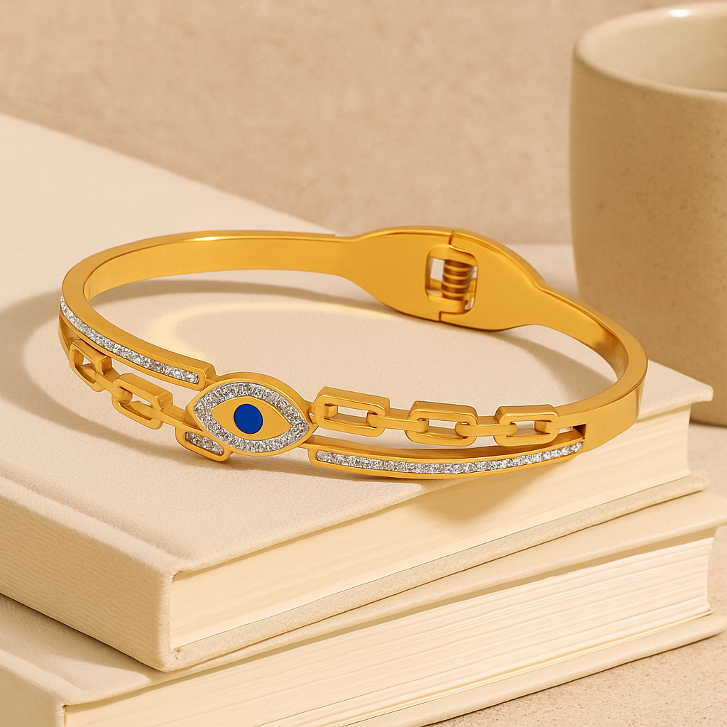 Gold bracelet with a blue gemstone on a stack of books next to a beige mug.