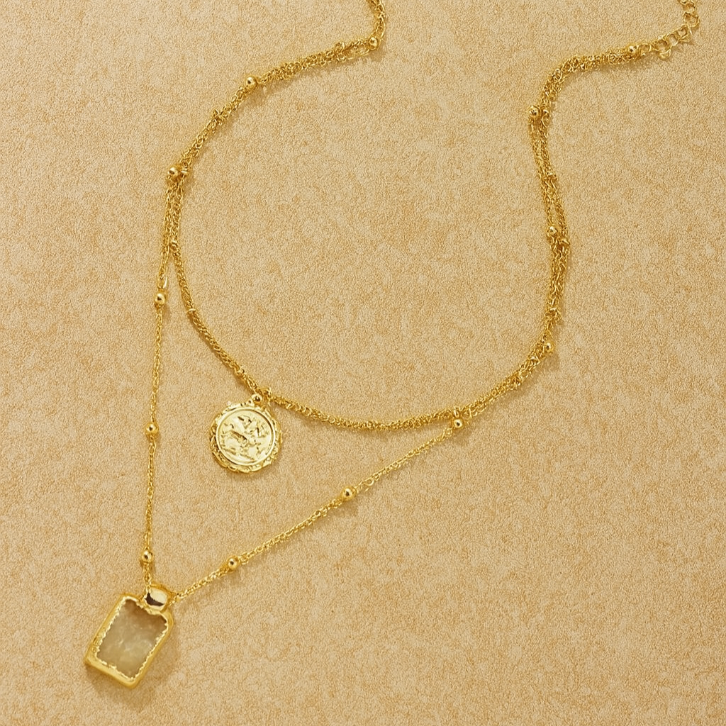 Gold necklace with pendant on a beige background