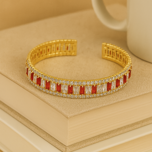 Gold bracelet with red and white stones on a beige surface