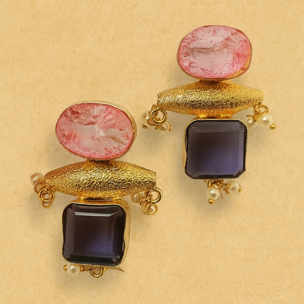 Pair of earrings with pink and black stones on a beige background