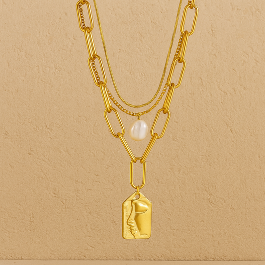 Gold necklace with pendant and bracelet on a beige background