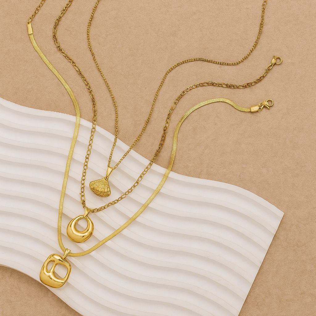Three gold necklaces with various pendants on a beige background