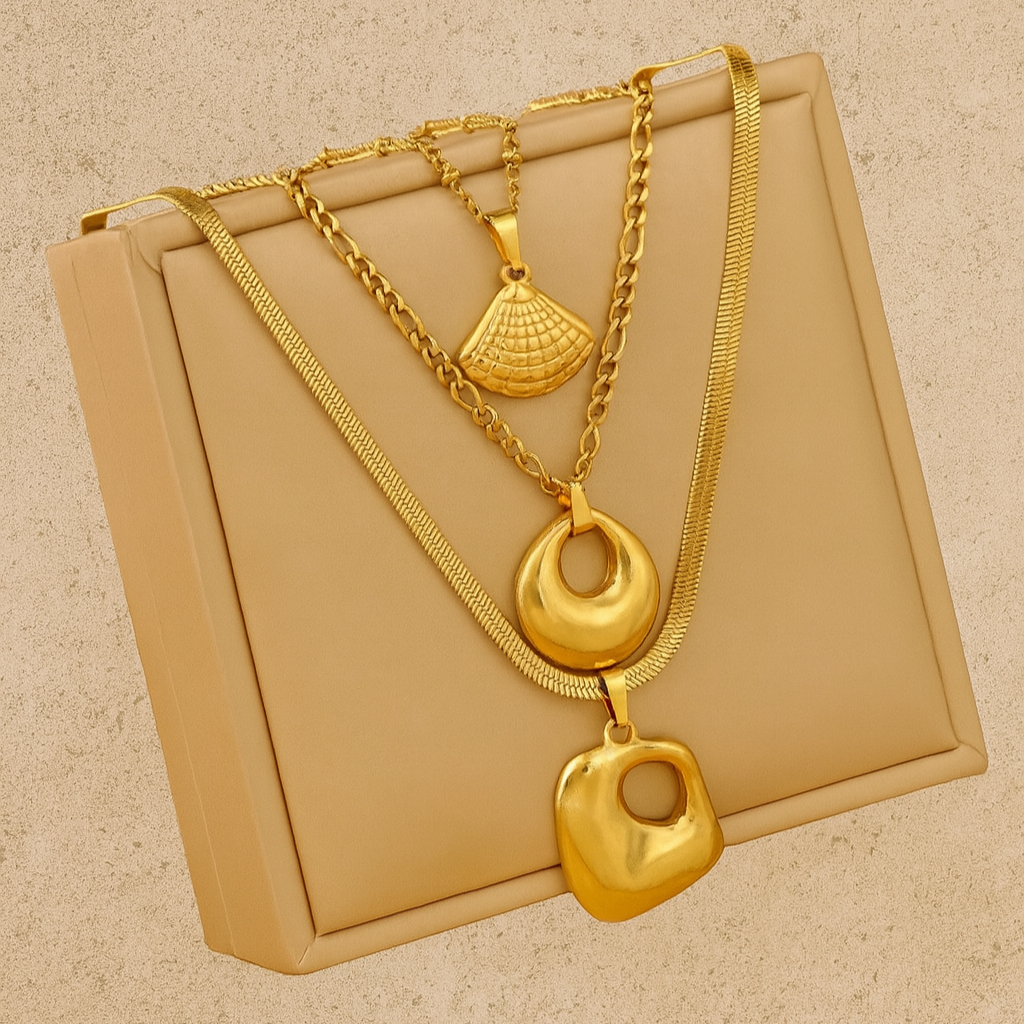 Gold necklaces with unique pendants on a beige box against a matching background