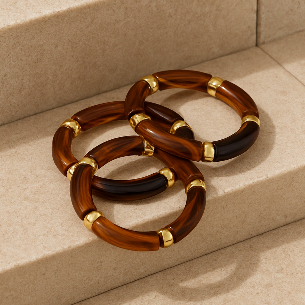 Set of three brown and gold bracelets on a beige surface