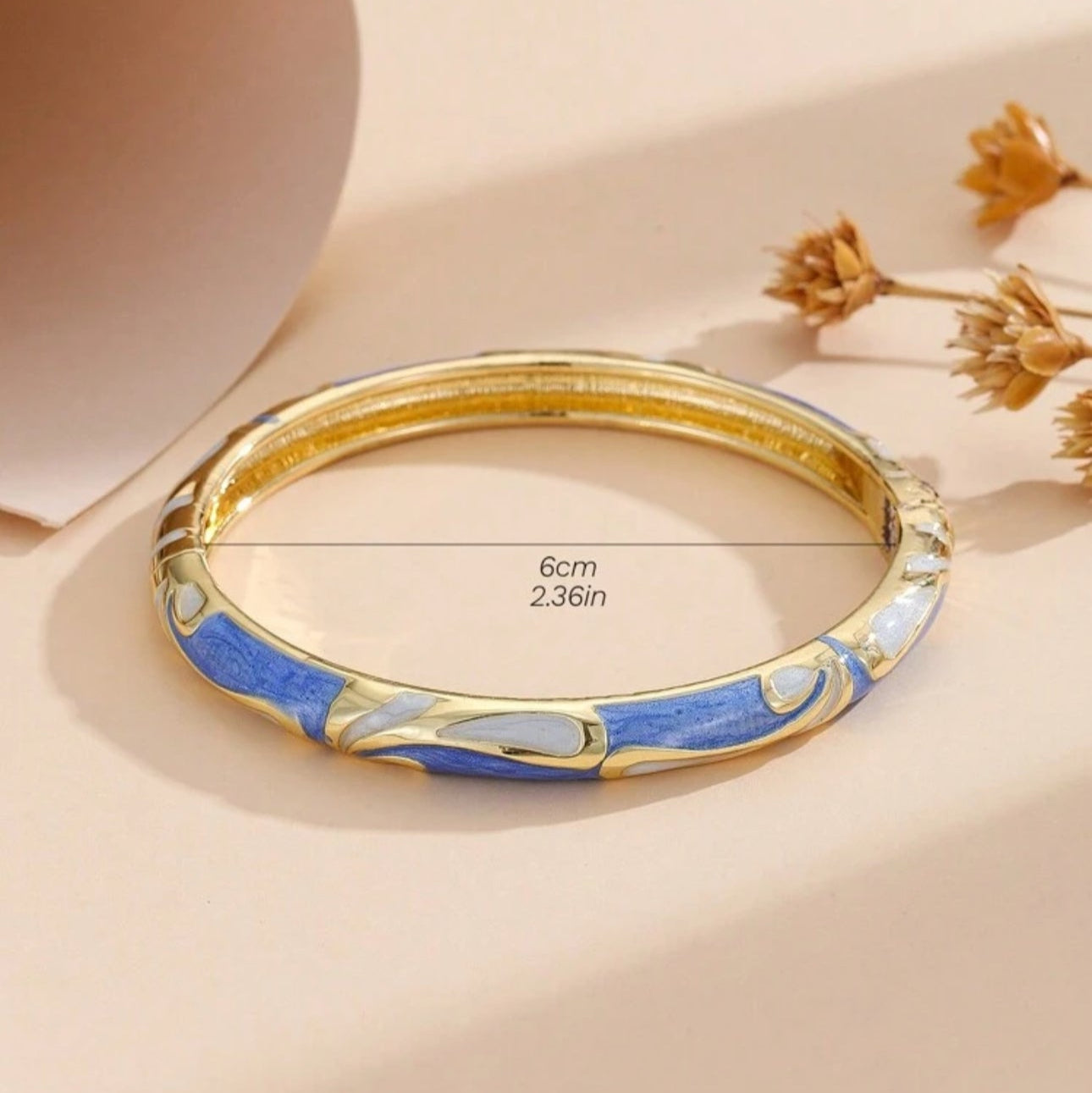 Gold and blue bracelet on a beige background with measurement text