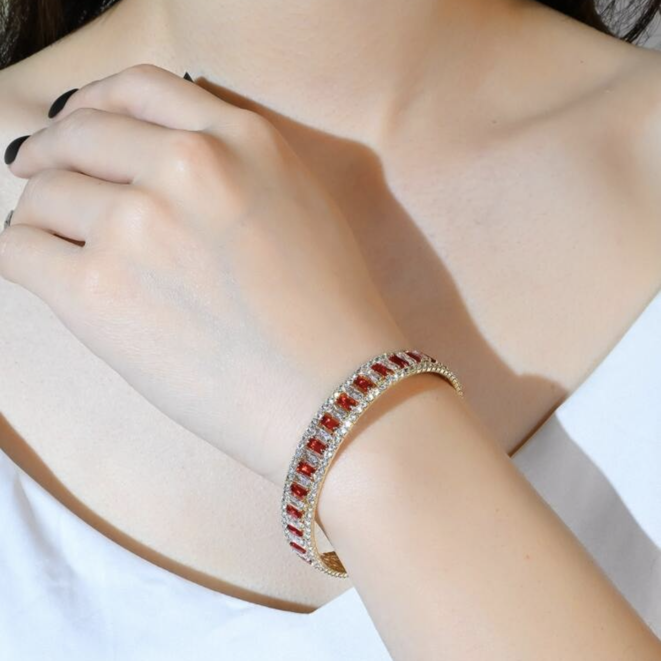 Close-up of a person wearing a red and gold bracelet on a white background
