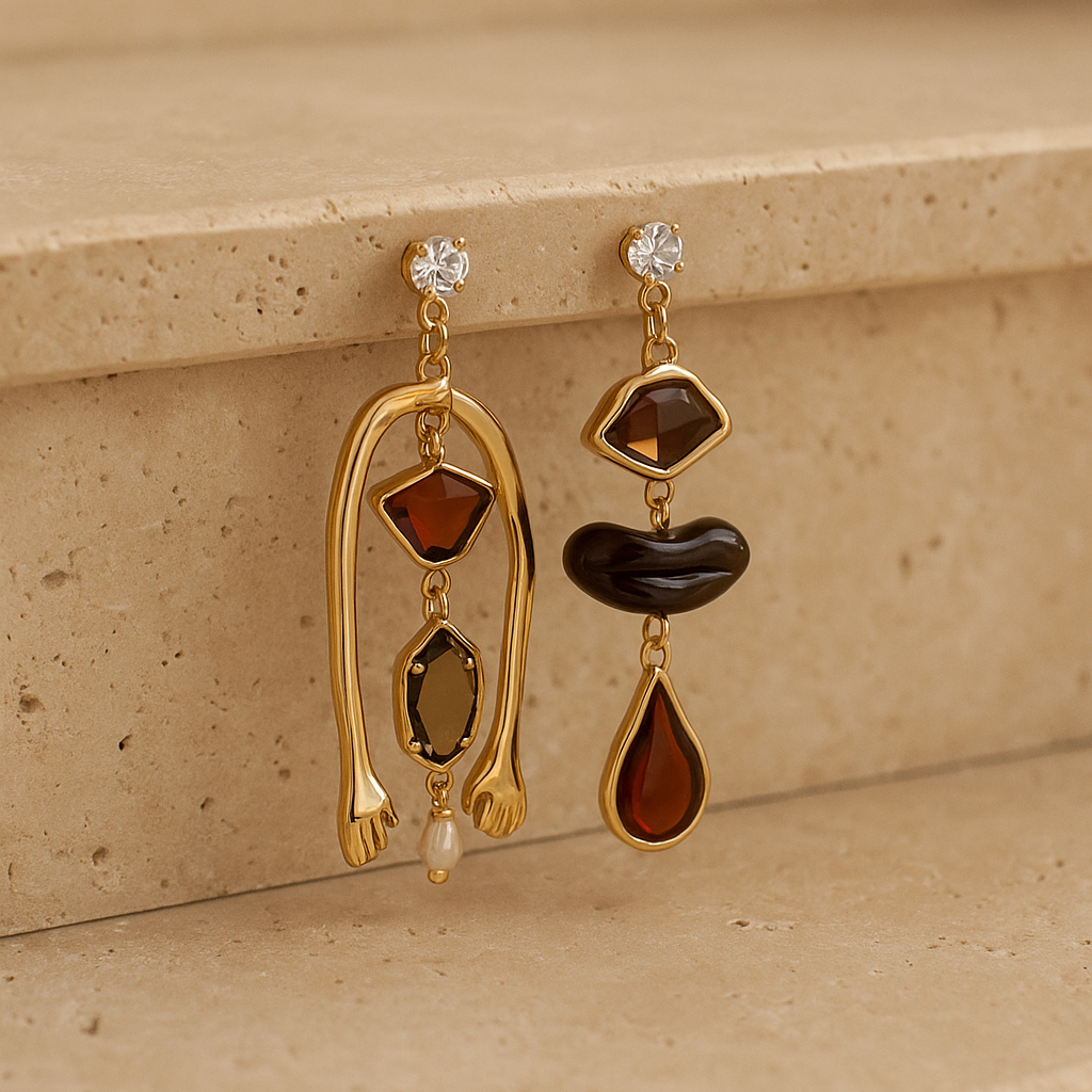 Pair of gold earrings with brown and clear stones on a beige surface