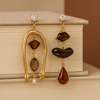 Gold earrings with brown gemstones on a beige surface