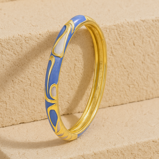 Gold ring with blue design on a beige stone surface