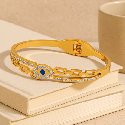 Gold bracelet with a blue gemstone on a stack of books next to a beige mug.