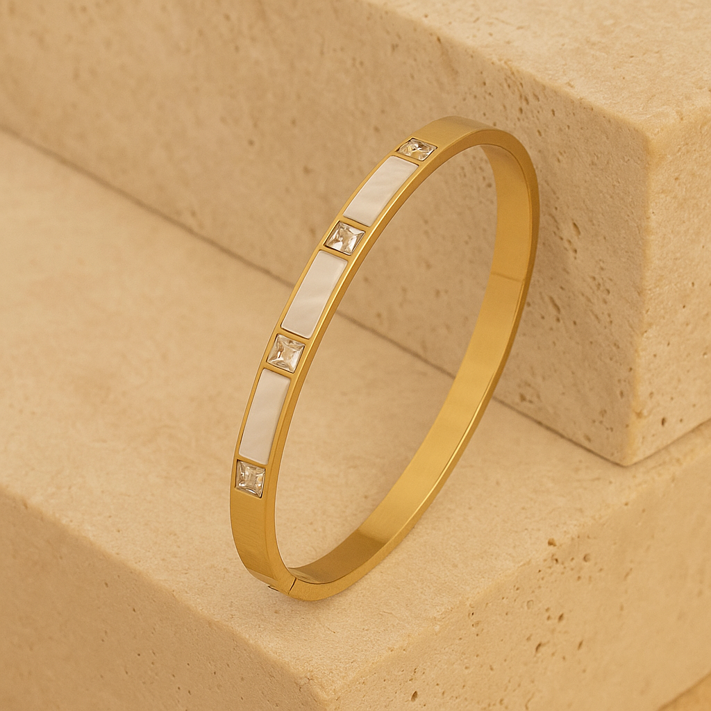 Gold bracelet with embedded stones on a beige stone surface