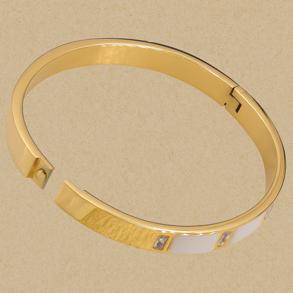Gold bracelet with a textured band on a beige background