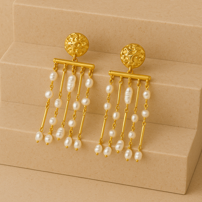 Gold earrings with pearl drops on a beige staircase