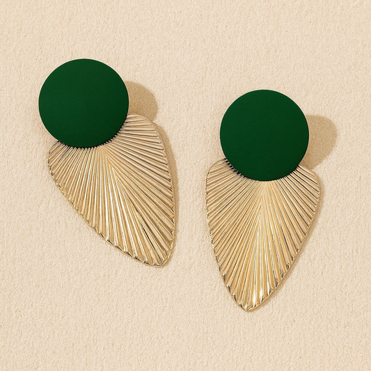 Pair of earrings with green circular tops and gold leaf-shaped bottoms on a beige background