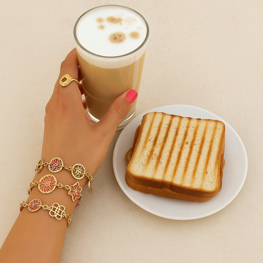 Hand holding a glass of latte with a grilled sandwich on a plate, both on a beige background